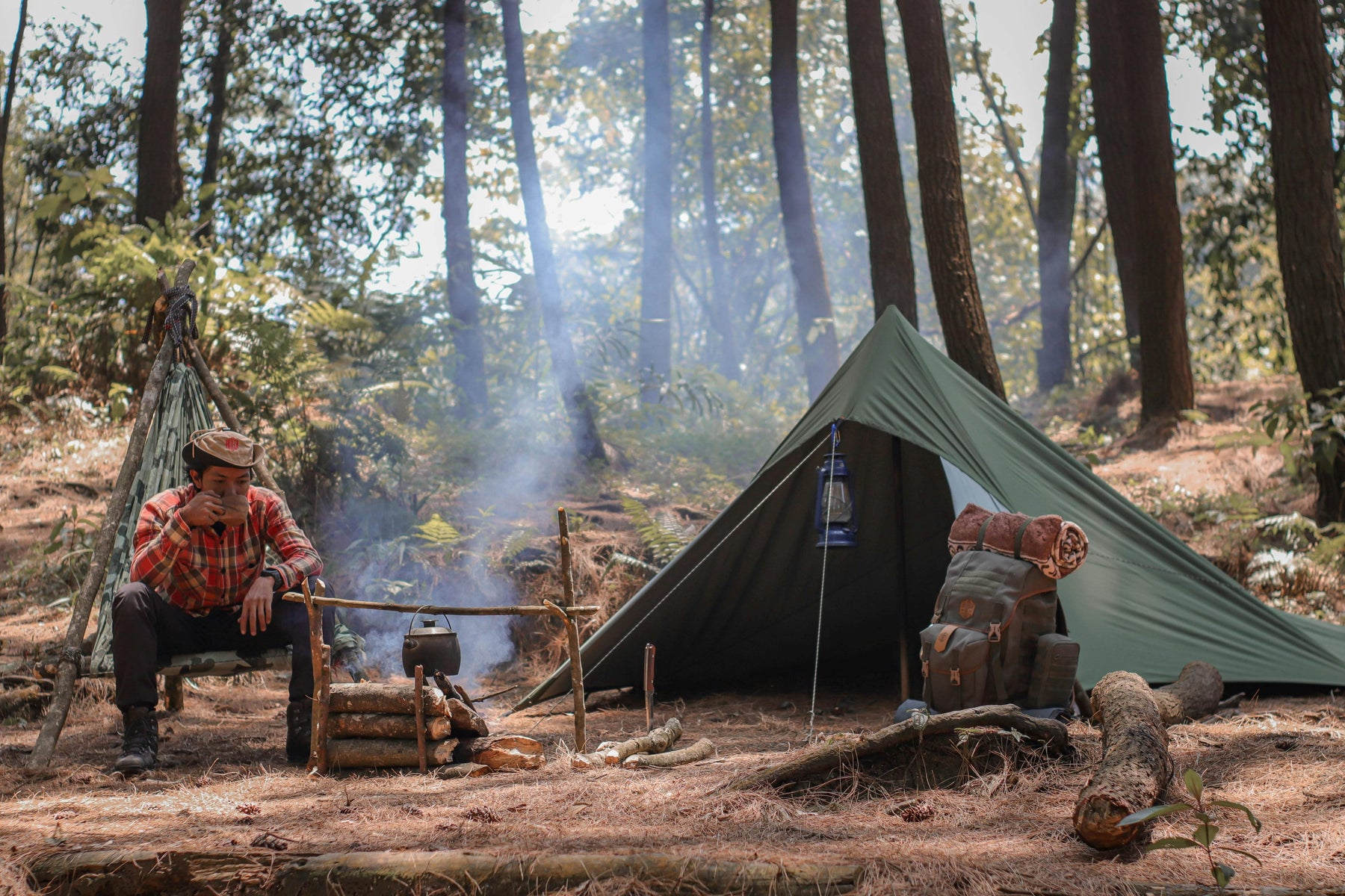 Bushcraftkamp met tarp, vuur en basisuitrusting in het bos