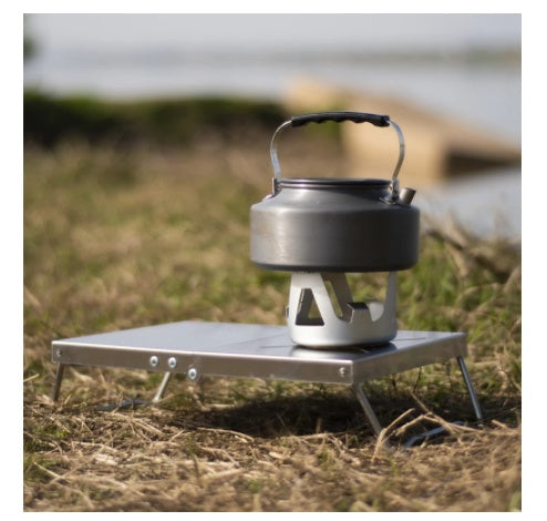Kooktafel met waterketel op een gasbrander, buiten in het gras