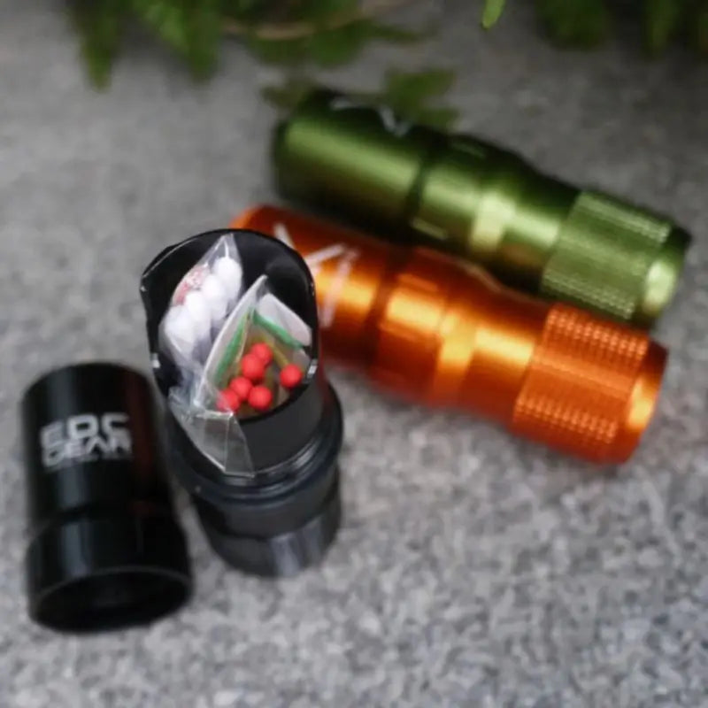 EDC capsules in groen, oranje en zwart met kleine noodspullen