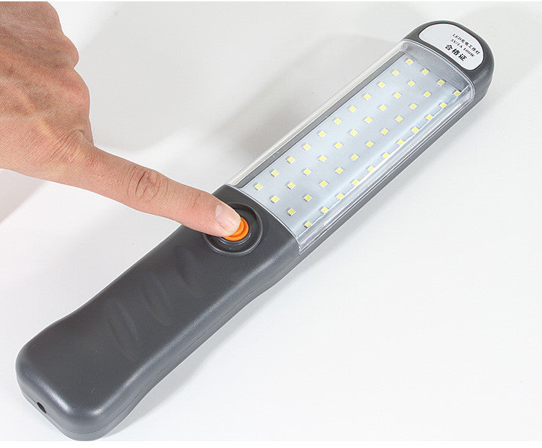 Vinger drukt op de aan-uitknop van de LED-werklamp