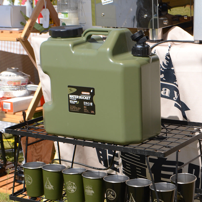 Legergroene waterjerrycan 18 liter op een kampeerrek met bekers